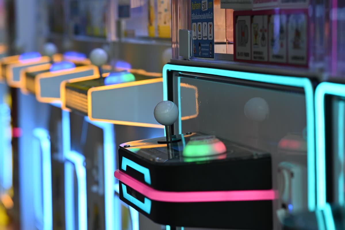 DFC 0797 Close-up of a row of retro arcade game joysticks glowing with neon blue and pink lights — 彩京 Memories 발매일·예약 일정